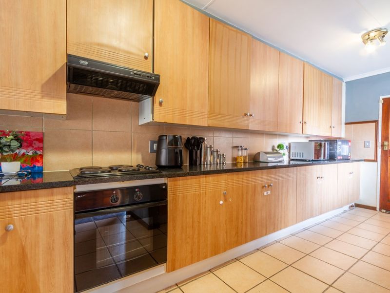 A functional kitchen featuring light wood cabinetry, granite countertops, a built-in oven, gas hob, and tiled flooring with a neutral backsplash.