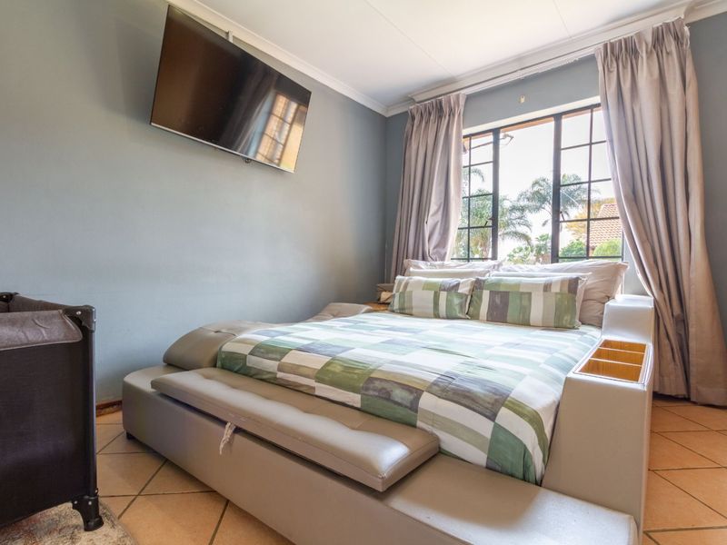 A bedroom featuring tiled flooring, a window with security bars, and coved ceiling details.