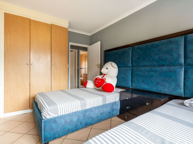 A bedroom featuring built-in wooden cupboards, tiled flooring, and a direct doorway leading to an adjoining bathroom.