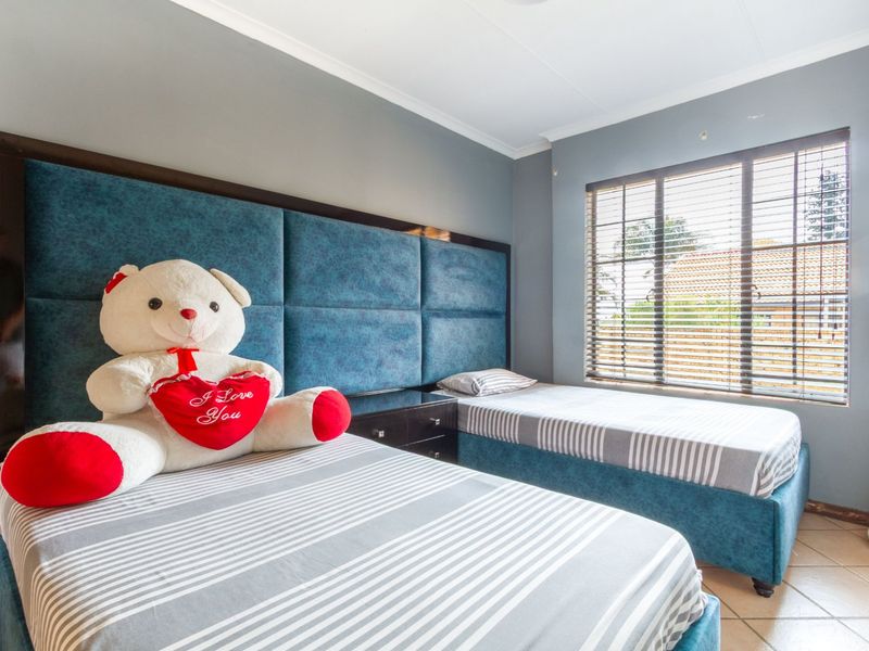 A bedroom featuring tiled flooring, cove cornicing, and venetian blinds, providing a functional space with neutral wall tones.