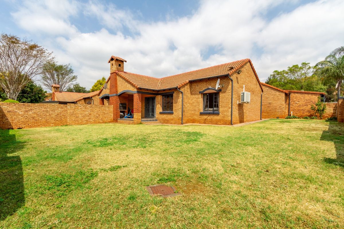 Rear view of a face brick townhouse featuring a private garden, built-in braai area, and secure access.