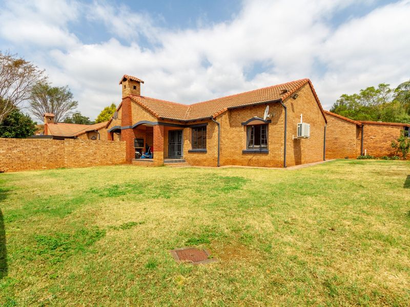 Rear view of a face brick townhouse featuring a private garden, built-in braai area, and secure access.
