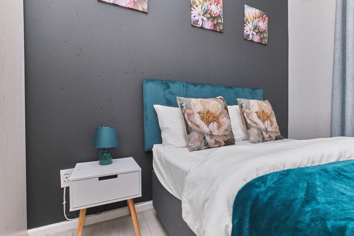 A well-maintained bedroom featuring a dark accent wall and neutral flooring.