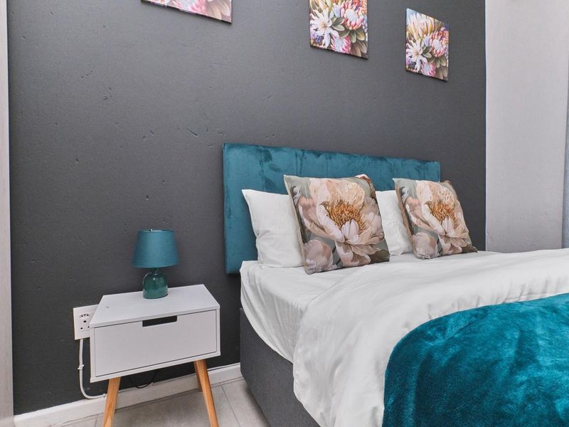 A well-maintained bedroom featuring a dark accent wall and neutral flooring.