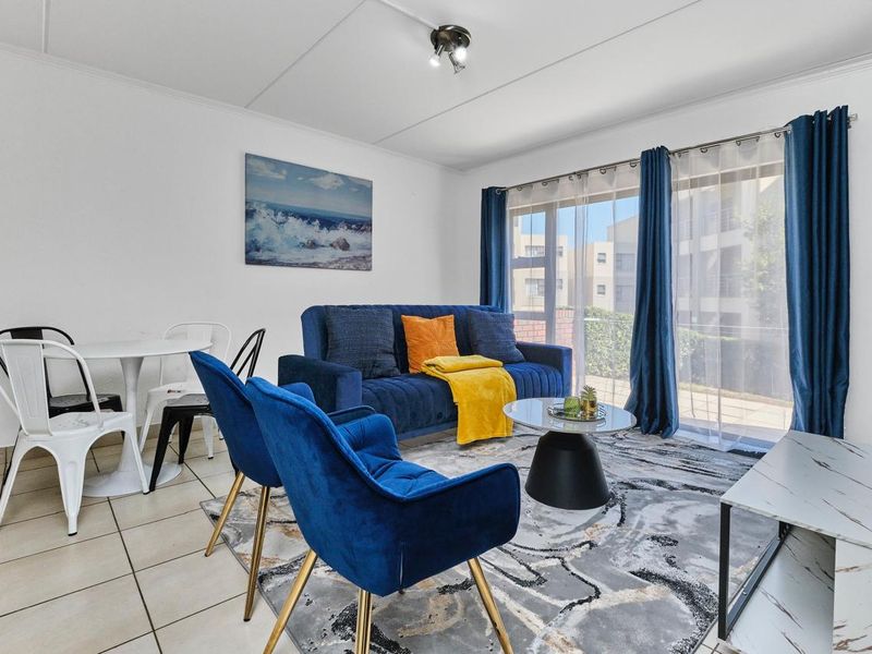 Bright open-plan living area featuring tiled flooring and large sliding glass doors that provide access to the exterior.