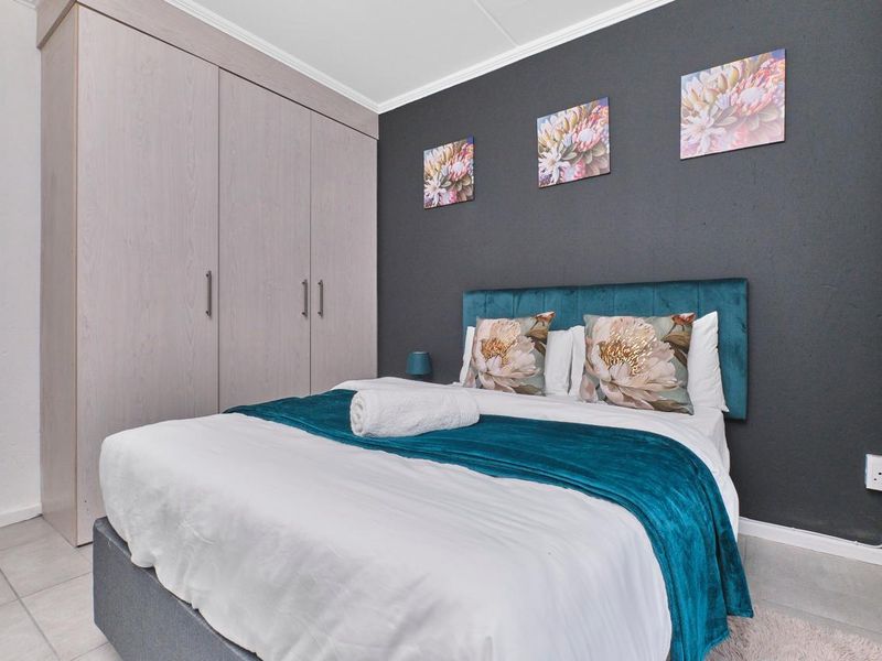 A well-maintained bedroom featuring built-in cupboards, tiled flooring, and a feature wall, offering a clean and functional living space.