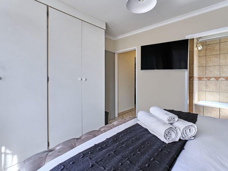 A bedroom featuring built-in cupboards, coving, and direct access to an en-suite bathroom with tiled finishes.