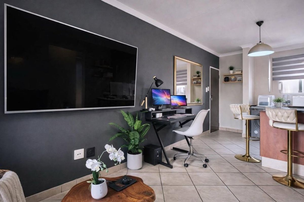 Modern open-plan living area featuring tiled flooring, a dark accent wall, and a functional kitchen breakfast bar with pendant lighting.