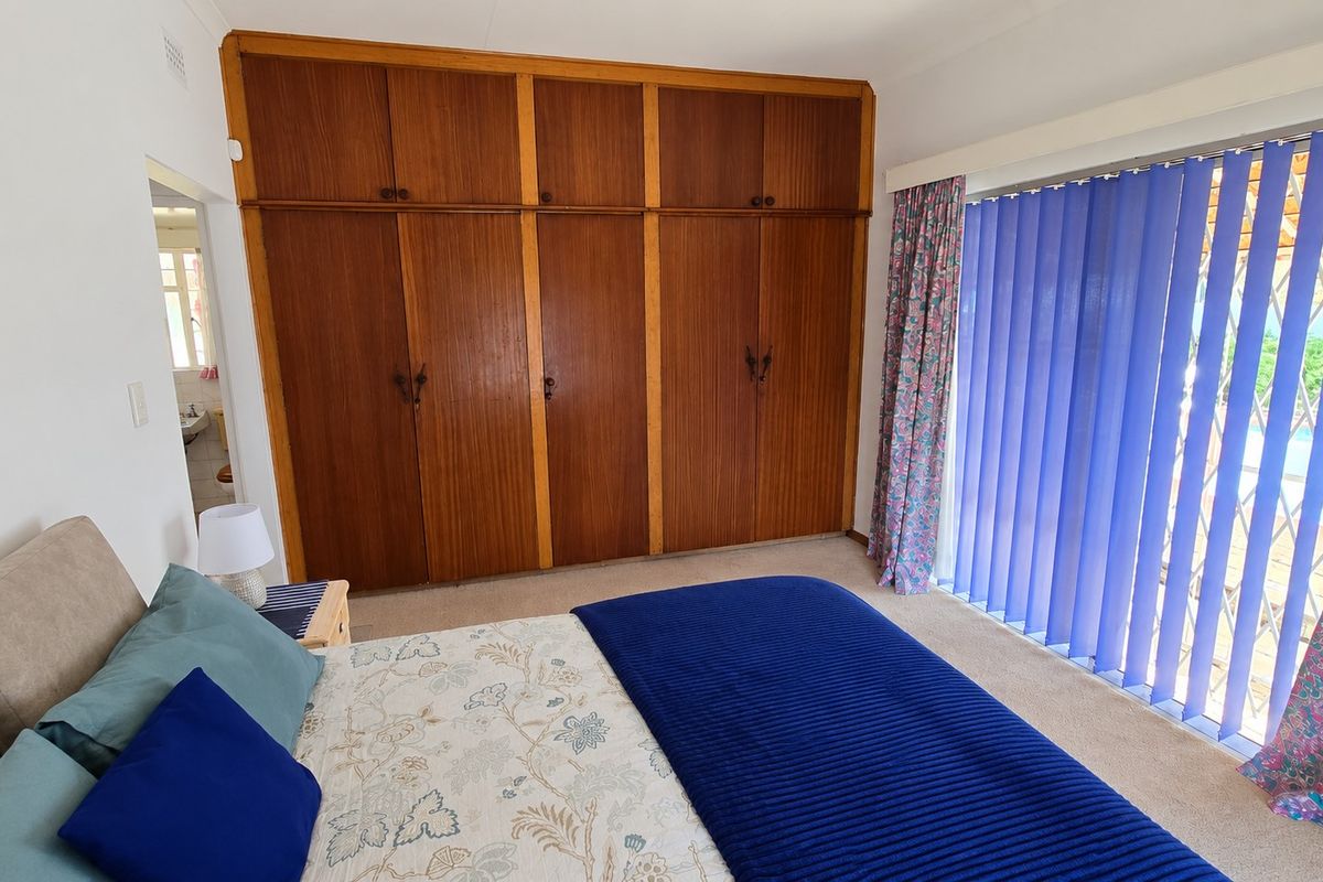 A bedroom featuring built-in wooden wardrobes and a large sliding glass door providing access to the outdoor area.