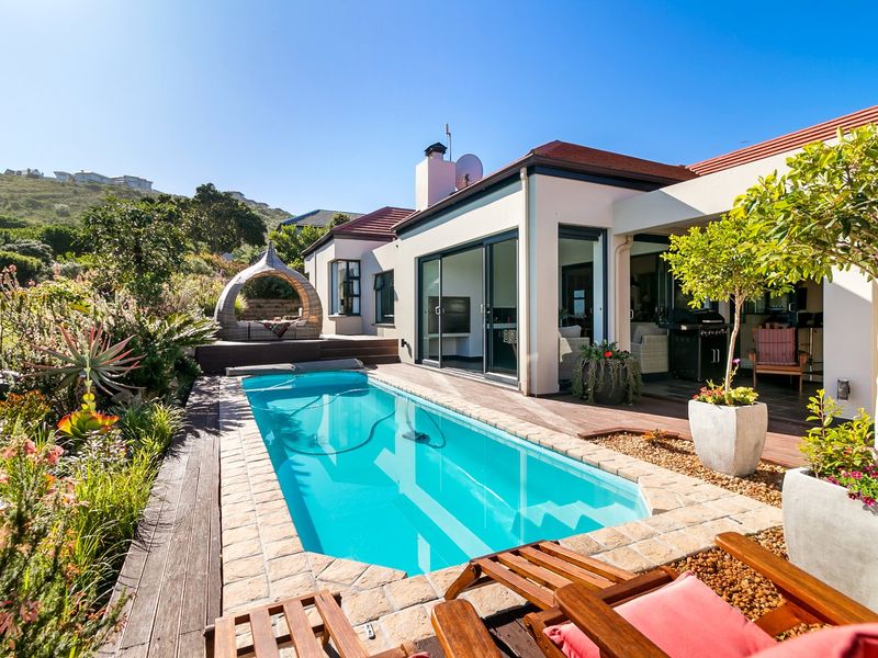 A well-maintained outdoor pool area featuring stone coping, timber decking, and seamless access to the covered patio and main living space.
