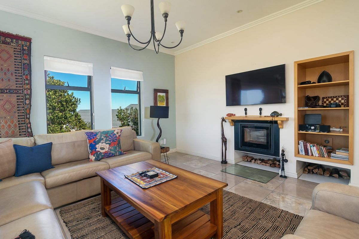 A comfortable living room featuring a built-in fireplace, integrated shelving, tiled flooring, and large windows providing natural light.