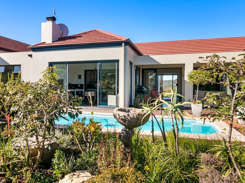 Rear exterior view of the house featuring a swimming pool, landscaped garden, and sliding glass doors leading into the living area.