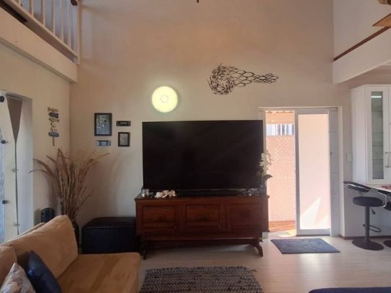 Spacious open-plan living area featuring a modern kitchen with island, tiled floors, and a mezzanine level overlooking the main living space.