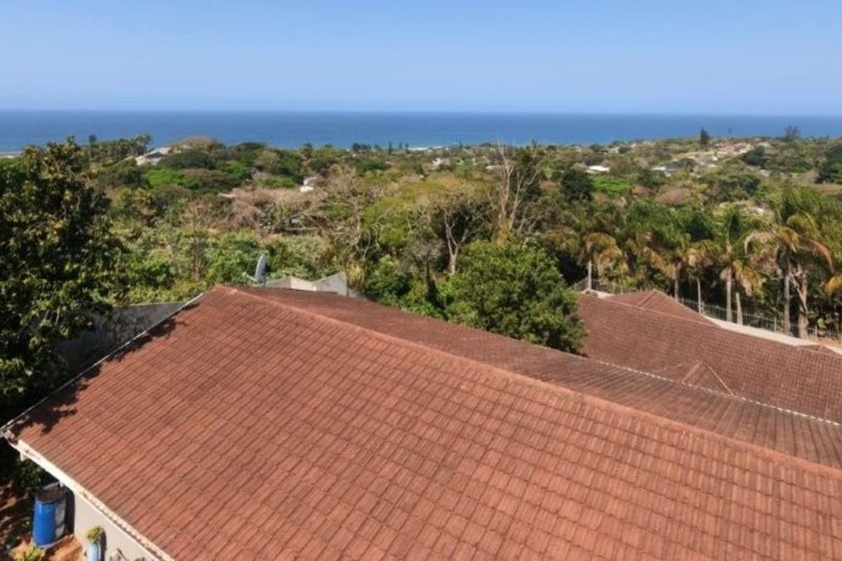 Aerial view of the property roofline showcasing the surrounding coastal landscape and ocean horizon.