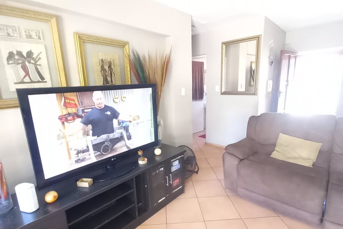 A living room area featuring tiled flooring and neutral wall finishes, providing a functional space with direct access to the home entrance.