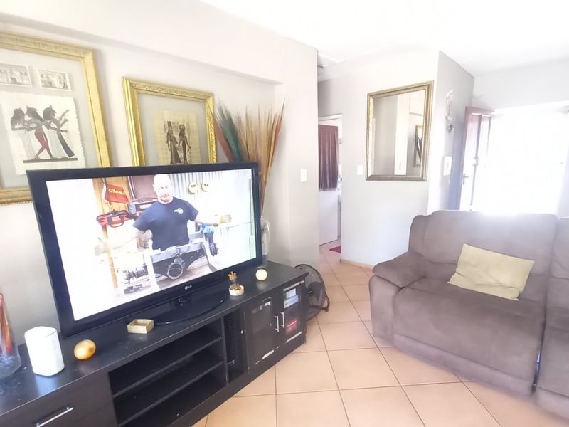 A living room area featuring tiled flooring and neutral wall finishes, providing a functional space with direct access to the home entrance.