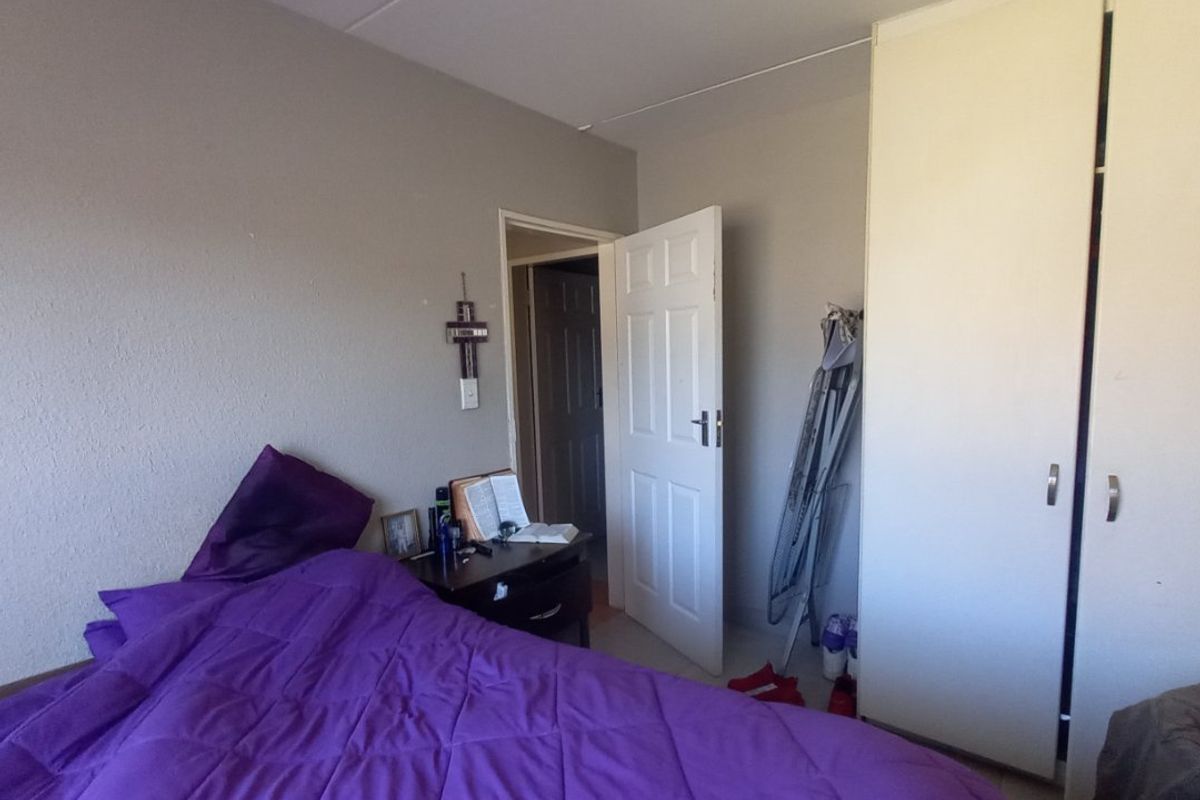 A standard bedroom featuring neutral wall finishes, a built-in wardrobe, and a panel door leading to the hallway.