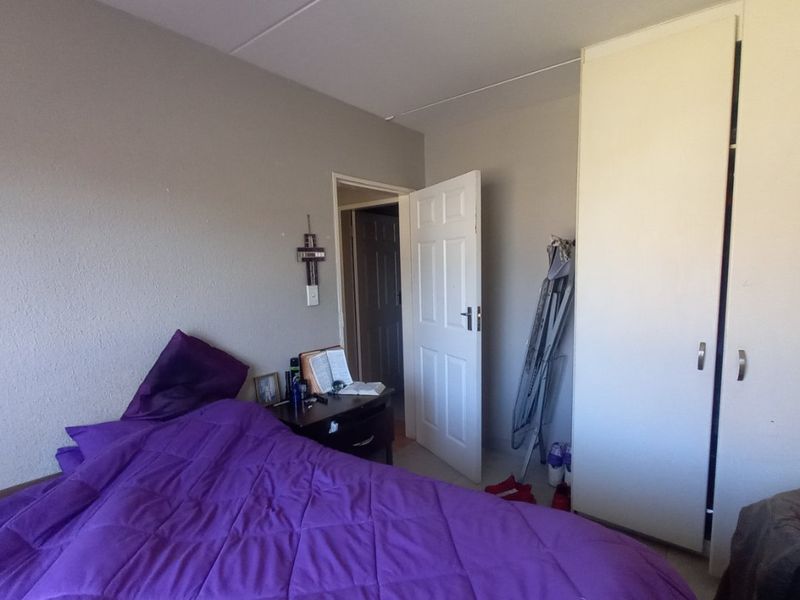 A standard bedroom featuring neutral wall finishes, a built-in wardrobe, and a panel door leading to the hallway.