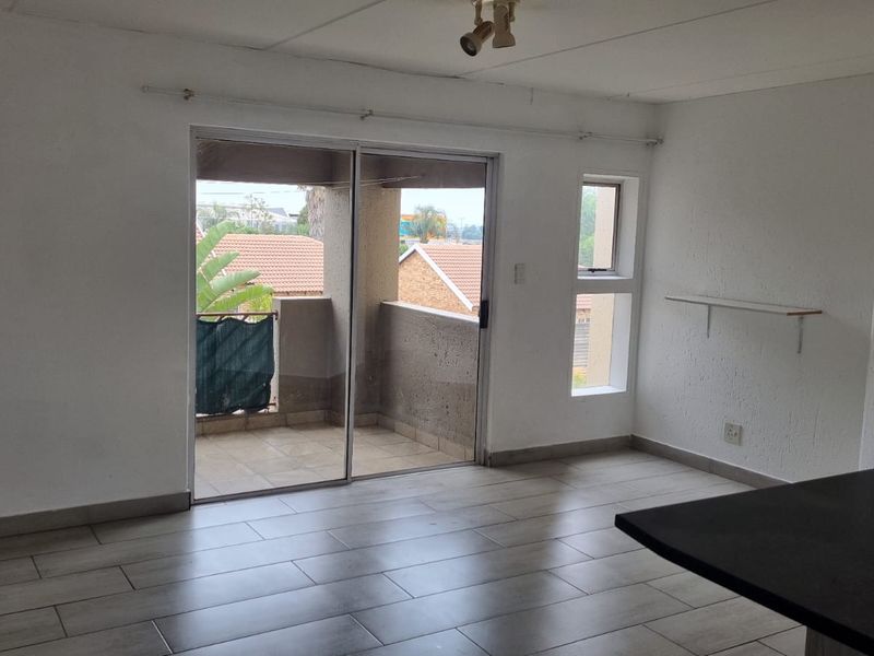 Open plan living area featuring tiled floors, a breakfast bar, and sliding glass doors leading to a private balcony.