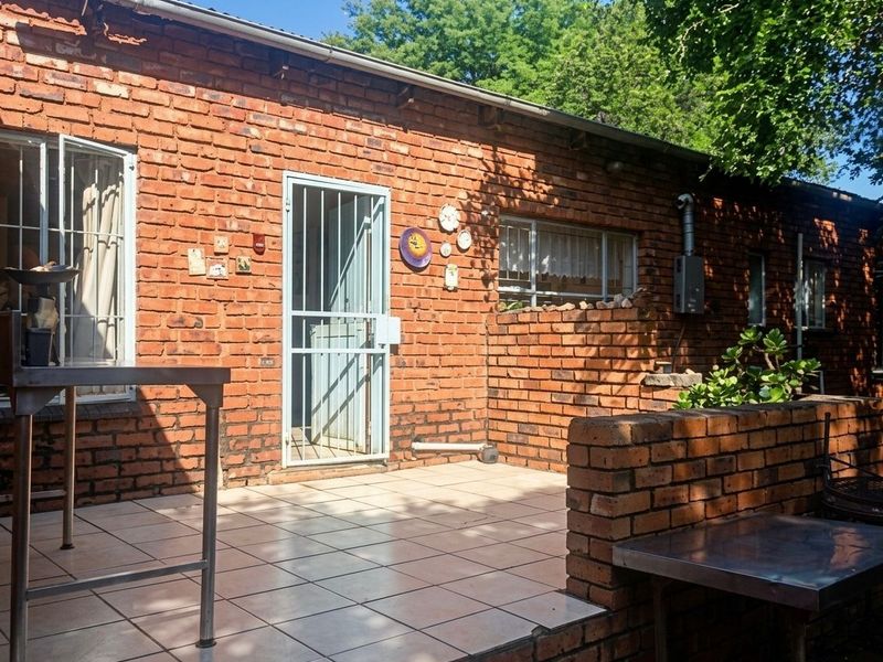 A rustic outdoor patio area featuring exposed brick walls, tiled flooring, and a secure entrance, offering a functional space for outdoor living.