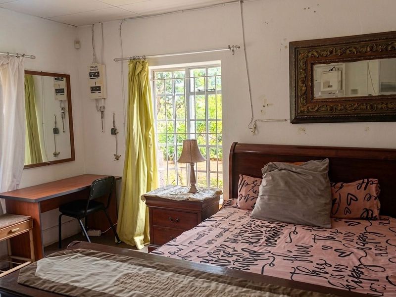 A bedroom featuring security bars on the window and exposed electrical conduit, requiring cosmetic updates to improve the overall finish and aesthetic appeal.