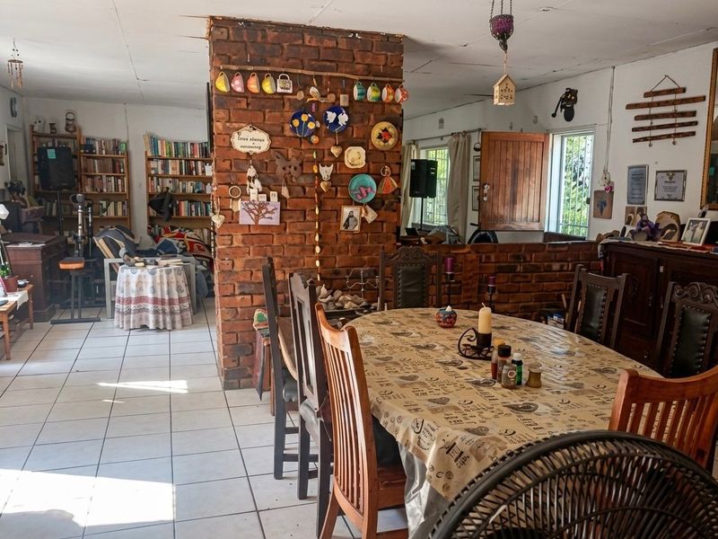Open-plan living and dining area featuring a central exposed brick pillar, ceramic tiled flooring, and built-in shelving units.