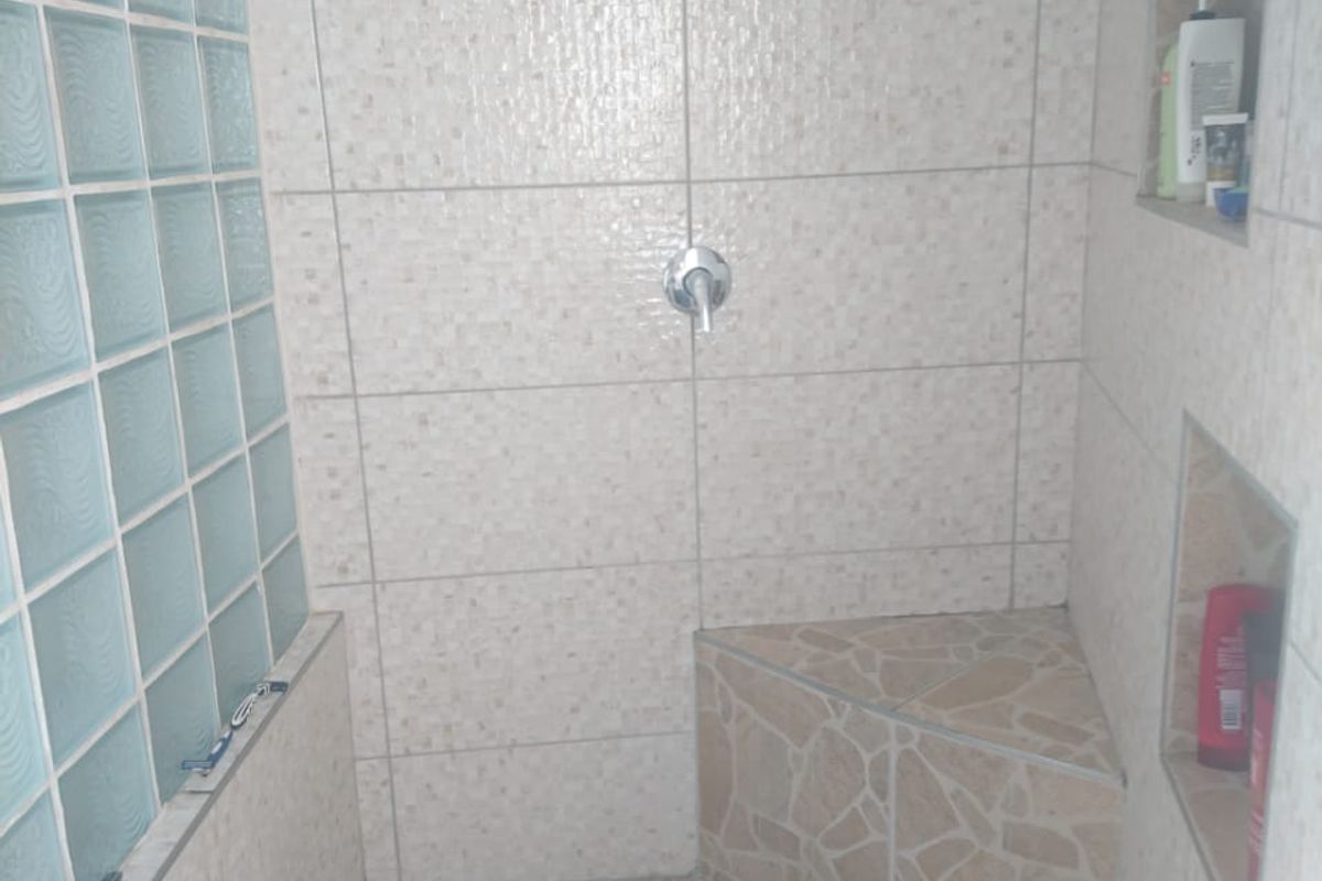 A tiled shower enclosure featuring a built-in corner bench, recessed storage niches, and a decorative glass block wall.