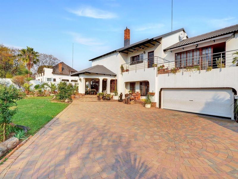 A well-maintained double-story residence featuring a paved driveway, integrated garage, and an upper-level balcony overlooking a landscaped front garden.