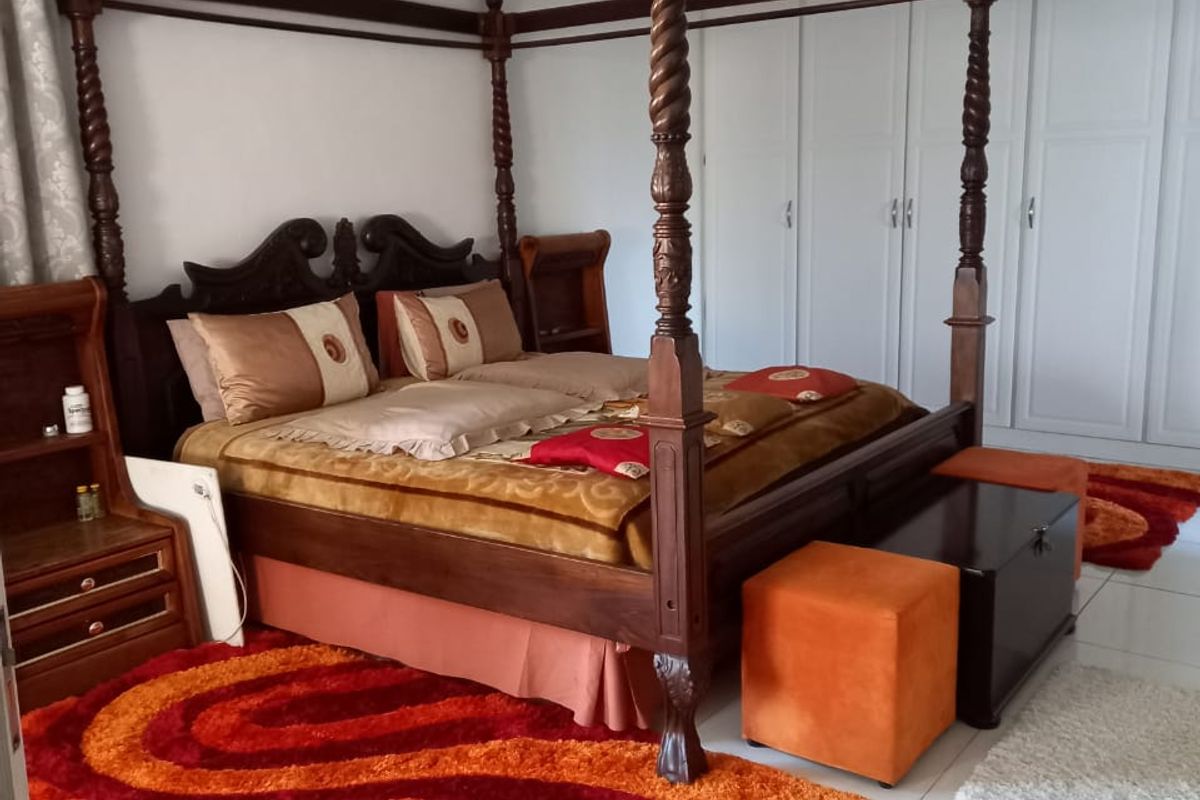 Spacious bedroom featuring neutral tiled flooring and extensive built-in white cabinetry for ample storage.