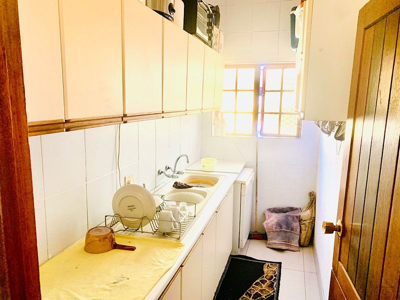 A functional scullery area featuring built-in cabinetry, a double sink, and tiled splashbacks, providing additional workspace and storage.