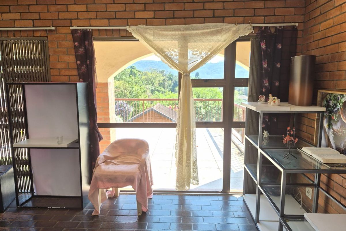 Living area featuring exposed brick walls, tiled flooring, and a large sliding glass door opening onto a balcony with scenic views.