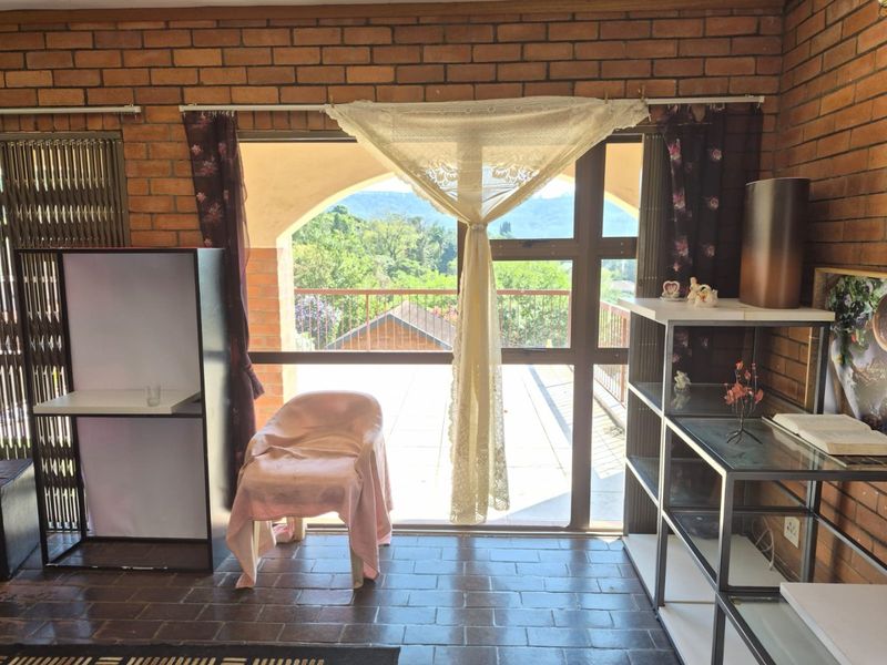 Living area featuring exposed brick walls, tiled flooring, and a large sliding glass door opening onto a balcony with scenic views.
