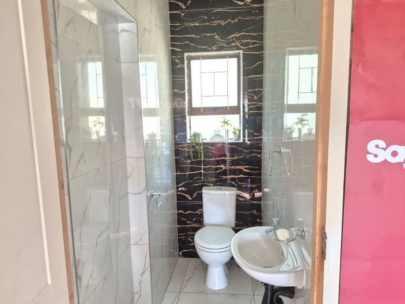 A compact, modern bathroom featuring contrasting black and white marble-style wall tiles, a pedestal basin, and a standard toilet.