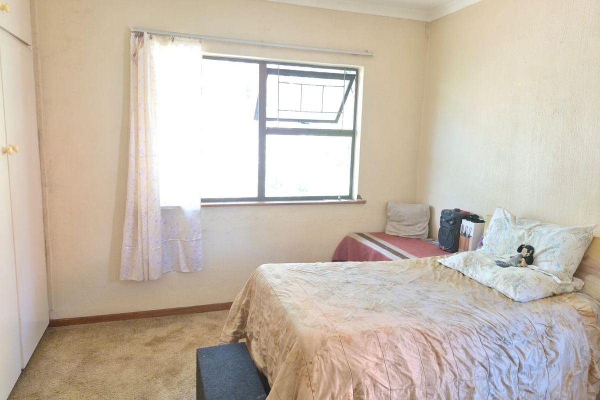 A bedroom featuring built-in wardrobe storage, carpeted flooring, and a window providing natural light.