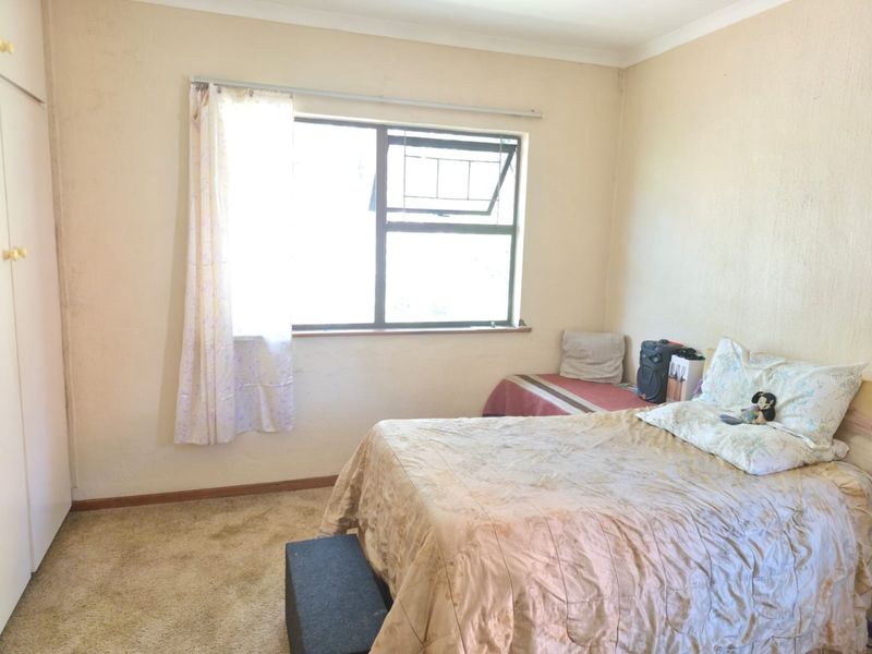 A bedroom featuring built-in wardrobe storage, carpeted flooring, and a window providing natural light.