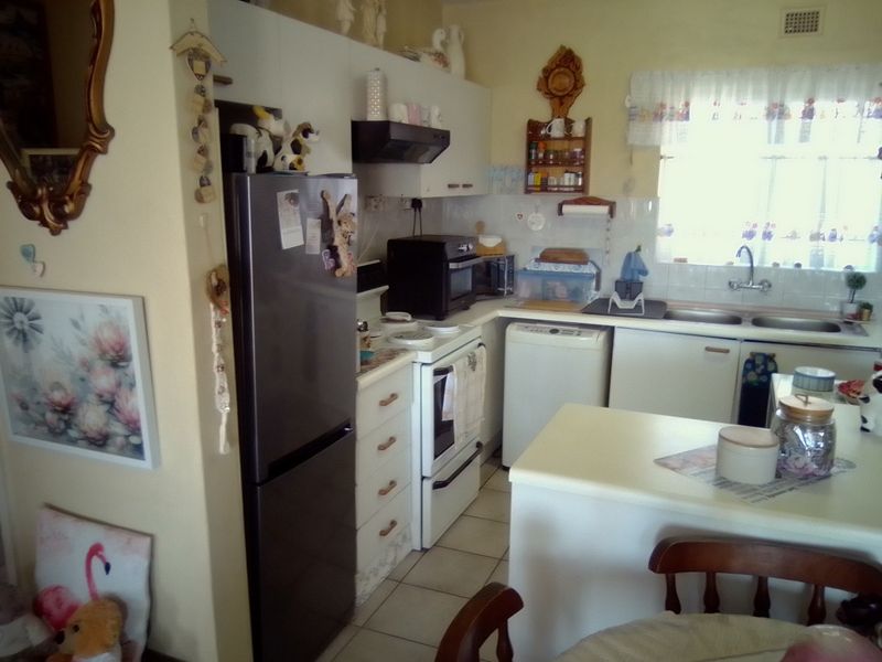 A functional kitchen featuring built-in cabinetry, a double sink, and tiled splashbacks, offering a practical layout for daily meal preparation.