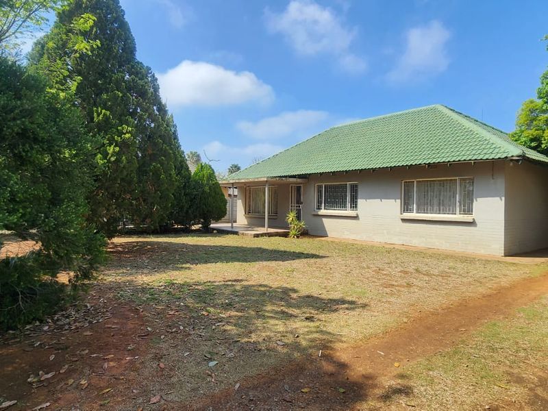 Front view of a single-story house featuring a green tiled roof, brick exterior, and a covered entrance porch set on a spacious garden plot.