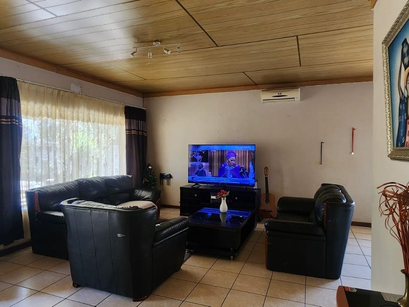 A living room featuring tiled flooring, a wood-paneled ceiling, and a wall-mounted split-system air conditioner.