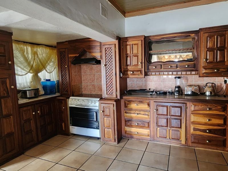 A traditional kitchen featuring extensive wooden cabinetry, tiled backsplash, and a freestanding oven, offering a classic layout with potential for modern updates.