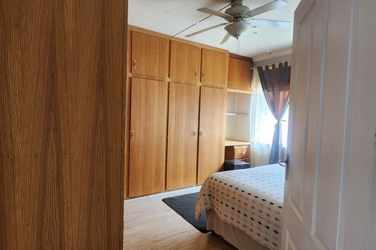 Bedroom featuring extensive built-in wooden cabinetry, a ceiling fan, and light-toned laminate flooring.