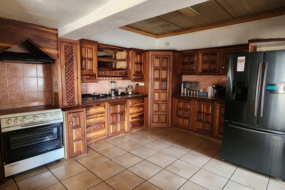 A traditional kitchen featuring extensive wooden cabinetry, tiled backsplash, and tiled flooring, offering a functional layout with a classic aesthetic.
