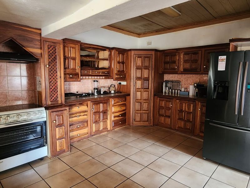 A traditional kitchen featuring extensive wooden cabinetry, tiled backsplash, and tiled flooring, offering a functional layout with a classic aesthetic.