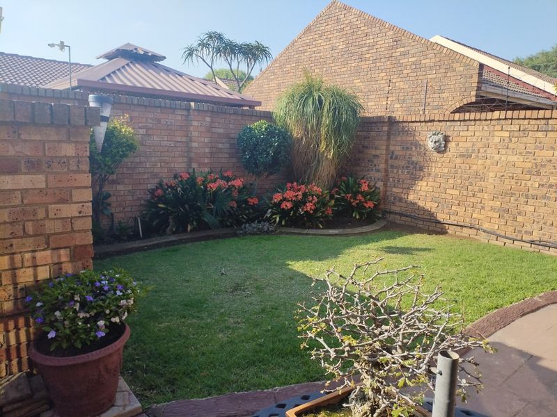 A private rear garden featuring a well-maintained lawn, established garden beds, and brick boundary walls, providing a secure and pleasant outdoor space.