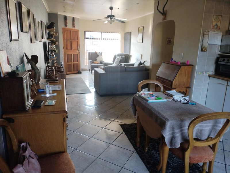 Open-plan living and dining area featuring tiled flooring, a ceiling fan, and an arched transition to the kitchen space.
