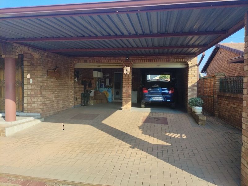 A covered brick garage and carport area with paved flooring, providing secure parking and additional storage space.