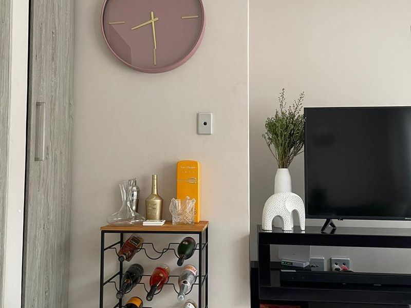 A living room area featuring neutral wall tones, tiled flooring, and a built-in cupboard with wood-grain finish.