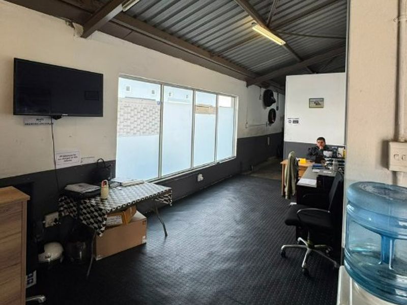 A functional commercial office space featuring exposed metal roofing, large windows for natural light, and durable rubberized flooring.