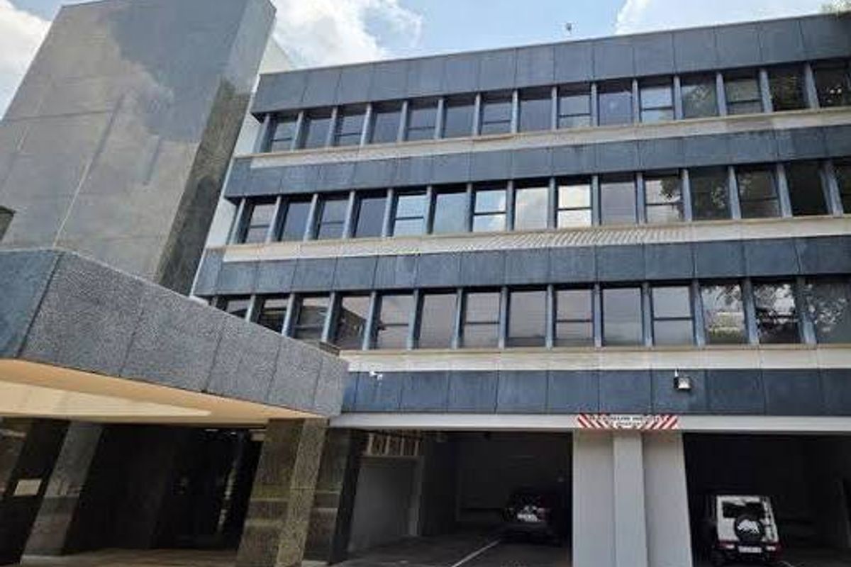 A professional view of a multi-story commercial building featuring granite cladding, large windows, and a dedicated covered parking entrance.