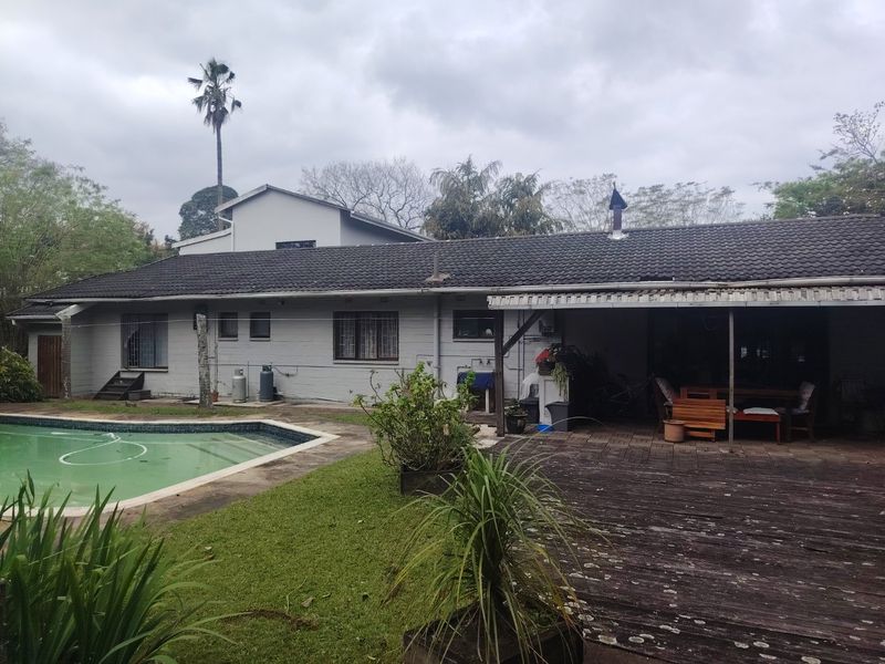 Rear view of the property featuring a swimming pool, covered patio area with timber decking, and a tiled roof structure.
