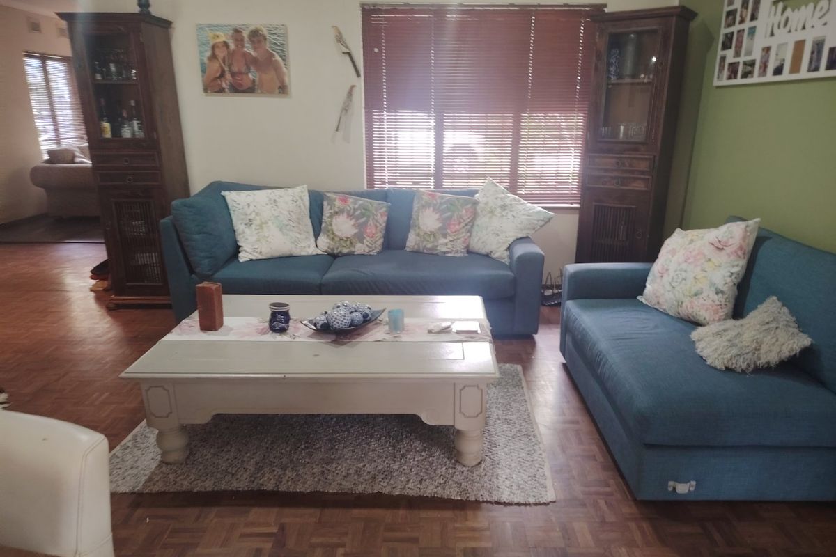 A comfortable living room featuring classic parquet flooring and venetian blinds, providing a warm and functional space for relaxation.